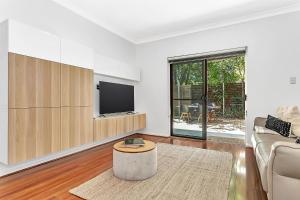 a living room with a couch and a tv at Secure Suite in Gated Complex, Courtyard, 5 Min CBD in Rose Park