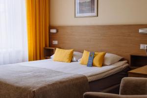 a hotel room with a bed with yellow pillows at Hestia Hotel Draugi in Riga