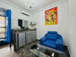 a living room with a blue couch and a table at CAMERHOME Banque SCB Cité des palmiers in Douala +100 photos