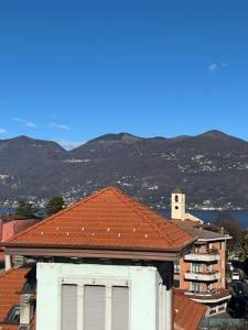 a building with a red roof with mountains in the background at Relax Luino vista lago Casa LEA in Luino