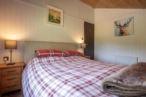 a bedroom with a bed with a red plaid blanket at Tesseyman Lodge in Bubwith