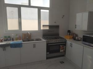 a kitchen with white cabinets and a stove top oven at منزل للإيجار اليومي in Ḩilf