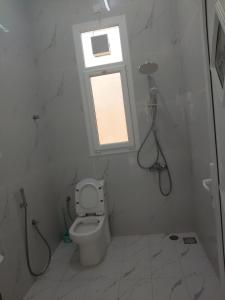 a white bathroom with a toilet and a window at منزل للإيجار اليومي in Ḩilf +12 photos
