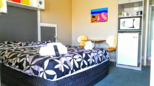 a bedroom with a bed with a black and white comforter at Astray Motel in Rotorua