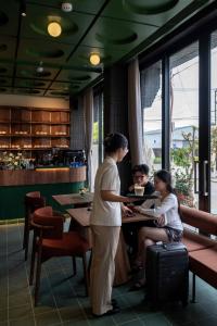 a woman and two children sitting at a table in a restaurant at Olwen Boutique Hotel in Danang +108 photos