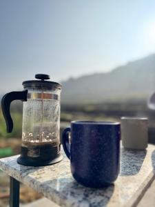 a coffee pot and a cup on a table at Calmsutra retreat in Sānkhu +2 photos
