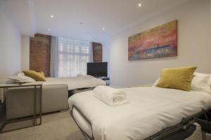 a room with two beds and a desk and a television at ChocoLets - The Lion Suite in York