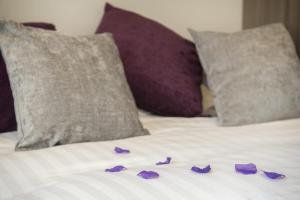 a pile of purple flowers on a bed with pillows at ChocoLets - The Quality Suite in York