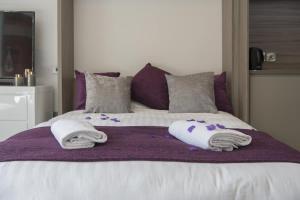 a bed with towels and pillows on a purple blanket at ChocoLets - The Quality Suite in York