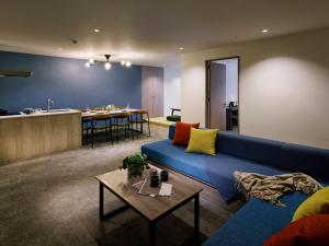 a living room with a blue couch and a kitchen at Minn STATION Ai Nagoya in Aoichō