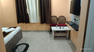 a room with a table and chairs and a tv at Hotel Tara Darshan in Tarapith