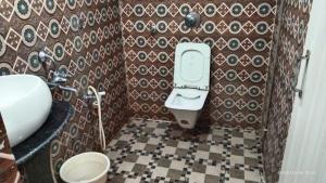 a bathroom with a toilet and a tile wall at Hotel Tara Darshan in Tarapith