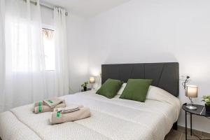 a bedroom with a large white bed with green pillows at Monte Tulum in Torrent +34 photos