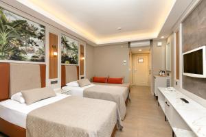 a hotel room with two beds and a flat screen tv at Club Hotel Phaselis Rose in Tekirova