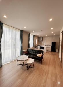 a living room with a couch and tables and a kitchen at 熊本Station one in Kumamoto