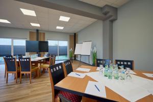 a conference room with tables and chairs and a screen at Hotel Viva Bröckel in Bröckel