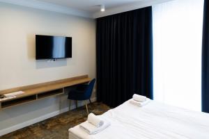 a hotel room with a bed and a tv on the wall at Hotel Przystań Przy Lesie in Lewiczyn