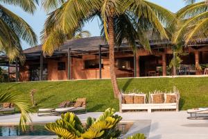 a resort with a palm tree and chairs and a pool at Adouna Bay in Cap Skirring