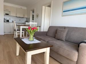 a living room with a couch and a table with flowers on it at Appartementhaus Hoppe in Sylt +11 photos