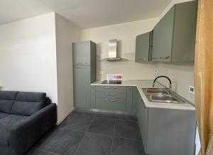 a kitchen with green cabinets and a sink and a couch at Ami Affittacamere 4 in Castel San Giovanni +7 photos