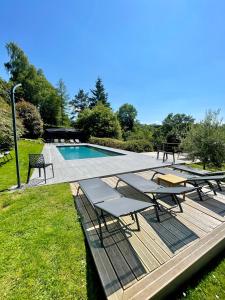 a swimming pool with picnic tables and benches in a park at LA FONTAINE ROMY in Genneville