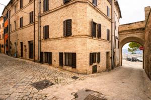 an old brick building with an arch in a street at Maison all'Arco in Corridonia