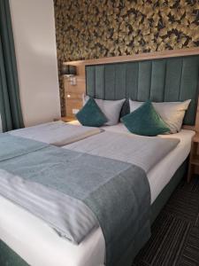 a bedroom with a large bed with a green headboard at Hotel Am Schwarzen Berg in Stade