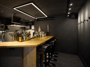 a bar in a restaurant with black walls and chairs at Minn STATION Ai Nagoya in Aoichō