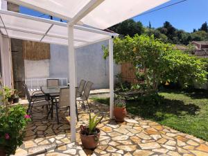a patio with a table and chairs under a white pergola at Sidari High Street Apartment in Sidari