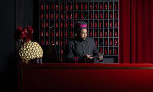 a man sitting at a table in front of a red curtain at Hotel Gotham Newcastle in Newcastle upon Tyne