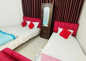 a room with two beds with red pillows and a mirror at Hotel Dhanmondi Prime in Dhaka +16 photos