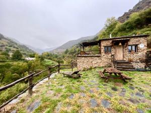 a stone building with a picnic table on a hill at CASA RURAL CORTIJO MOLINO ALTERO in Trevélez