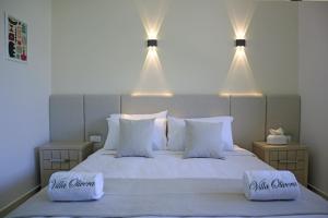a bedroom with a white bed with two lights above it at Villa Olivera Hotel in Tḩūm at Taḩtā