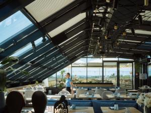 a woman standing in a restaurant with tables and chairs at Imperiall Resort&MediSPA-DOMKI PREMIUM in Sianozety