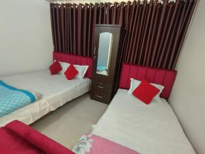 a bedroom with two beds with red pillows and a mirror at Hotel Dhanmondi Prime in Dhaka