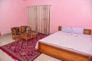 a bedroom with a bed and a chair and a table at Al Hera Resort in Sreemangal