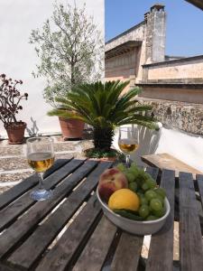 a bowl of fruit on a wooden table with wine glasses at Palazzo Luceri in Galatina