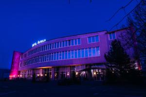 ein Gebäude, das nachts lila beleuchtet ist in der Unterkunft Hotel Aurelia in Timişoara