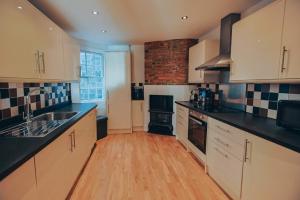 a kitchen with white cabinets and black counter tops at The Pelham Penthouse in Hastings
