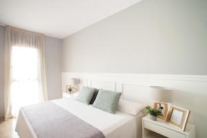 a white bedroom with a white bed and a window at The Orbit Apartments in Barcelona