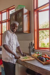 a man standing in a kitchen preparing food on a cutting board at Naramatisho Womens Centre & Maasai Cultural Stay in Makuyuni +26 photos