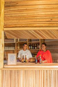two men sitting at a bar with bottles of beer at Naramatisho Womens Centre & Maasai Cultural Stay in Makuyuni