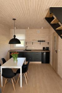 a kitchen and dining room with a white table and chairs at PoProstuDomki in Niechorze