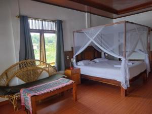 a bedroom with a canopy bed and a chair at Toba Sunset in Tuktuk Siadong