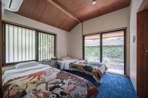 a bedroom with two beds and a window at TaaCH Okinawa in Nago
