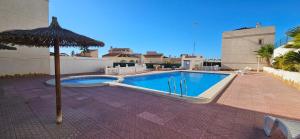 a swimming pool with an umbrella next to a building at Sunny Hill Apartment in Ciudad Quesada