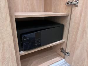 a microwave inside of a cupboard with a door at The Suites - St Pancras Hotel Group in London