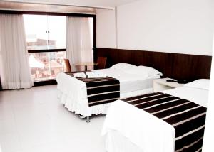 Habitación de hotel con 2 camas y ventana grande. en Tirol Praia Hotel en Natal