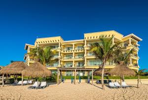 un hotel en la playa con sillas y sombrillas en Hotel Marina El Cid Spa & Beach Resort - All Inclusive, en Puerto Morelos