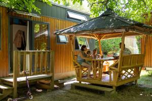 a group of people sitting at a gazebo outside a house at Camping la Plage Lot Vallée de la Dordogne Rocamadour in Meyronne